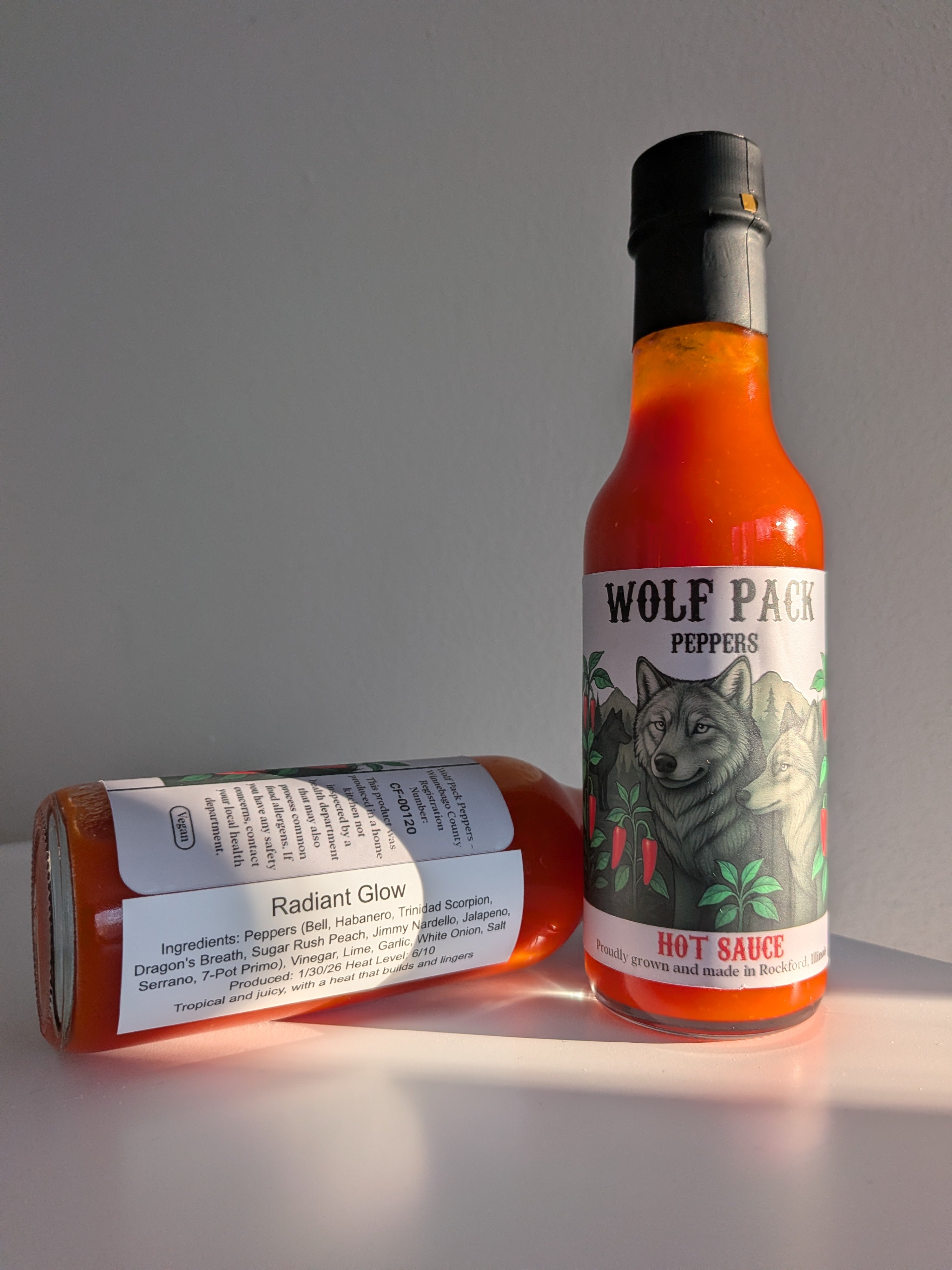 Two bottles of Wolf Pack Peppers Radiant Glow hot sauce