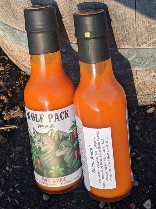 Two bottles of Wolf Pack Peppers Social Animal hot sauce.